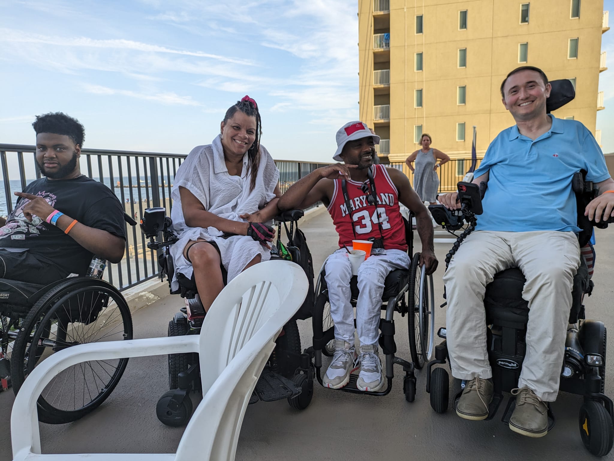 Four people in wheelchairs sitting and smiling together on concrete patio.